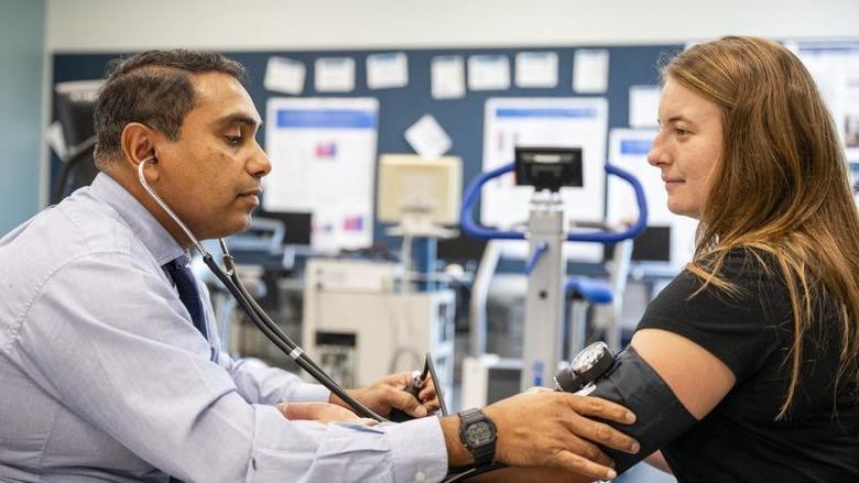 一个人戴着听诊器为另一个人测量血压